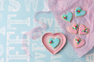 Heart-Shaped Valentine Cookies Decorated with Pink and Blue Icing on a Pink Heart-Shaped Dish on Blue Background.