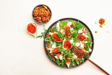 Fresh summer fig salad with white cheese, nuts, arugula and jam dressing on white table background, top view, copy space
