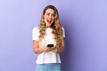 Young Brazilian woman isolated on purple background surprised and sending a message
