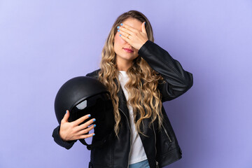 Young Brazilian woman holding a motorcycle helmet isolated on purple background covering eyes by hands. Do not want to see something