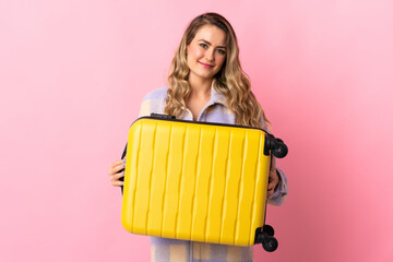 Young Brazilian woman isolated on pink background in vacation with travel suitcase