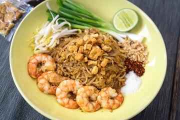 Prawn Pad Thai one of most famous thai food menu which is served in yellow ceramic plate. Food object photo, close-up and selective focus.