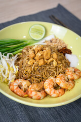 Prawn Pad Thai one of most famous thai food menu which is served in yellow ceramic plate. Food object photo, close-up and selective focus.