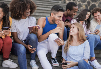 Group of young multiracial people having fun in the city with mobile phone - Millennial generation friends having social moment outdoor