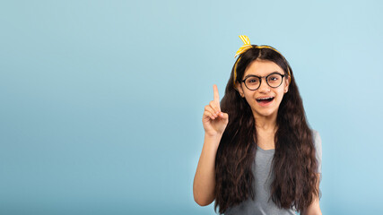 Excited Indian teen girl pointing finger up, finding creative solution to problem, having aha...