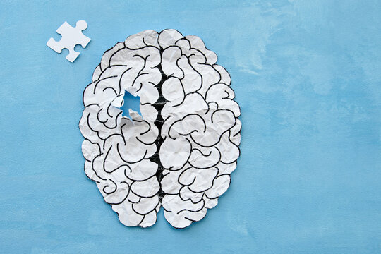 an attempt to connect the missing puzzle of the human brain on a blue background. A creative idea to solve a problem, memory loss, dementia or Alzheimer's disease. Mental health protection.