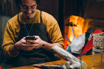 Fototapeta premium man using mobile phone while working in his workshop