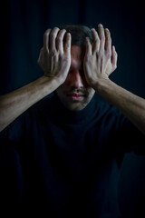 portrait of a young man covering his eyes with his palms so as not to see, disturbed by the light