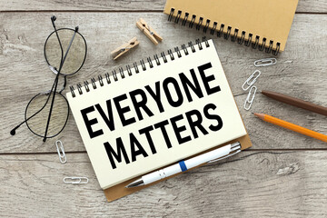 Everyone matters - text on open notepad on wooden table - obrazy, fototapety, plakaty