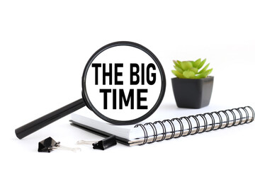 THE BIG TIME.text on a white background on a magnifying glass on a notepad and a plant