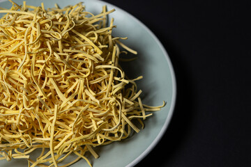 Egg noodles on a black background. Homemade traditional noodles on a plate. pasta