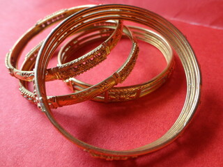 Gold bangles of india with red background                               