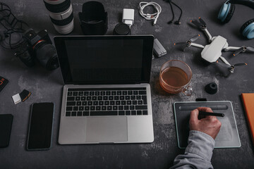 Man working on graphic tablet at workplace with different equipment