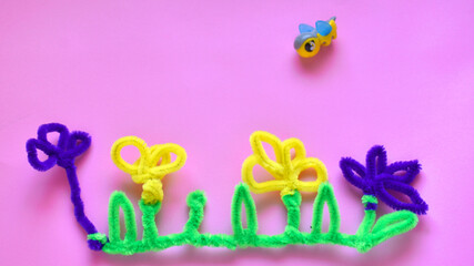 cute spring card flowers and a bee made of fluffy soft sticks on a pink background