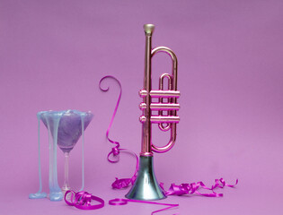 Pink and blue metallic trumpet party decorations, slimy in martini glass and on pink background, ...