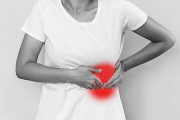 Cropped black and white shot of a young woman holding her side with her hands isolated on a white background. Sore side under the rib after training. Stomach pain © Марина Демешко