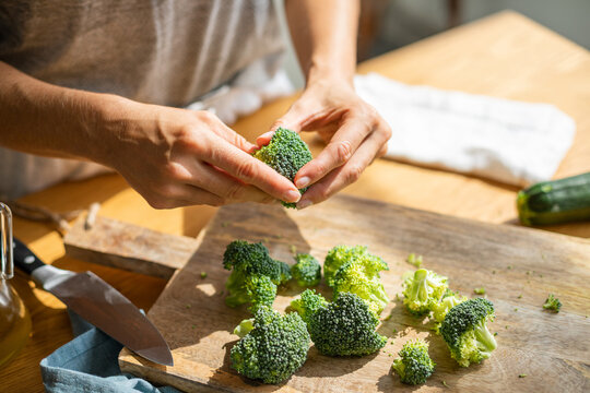 Unrecognizable cook preparing raw broccoli