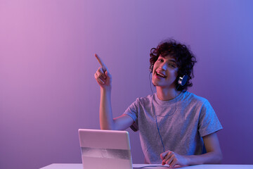 curly guy in headphones in front of laptop entertainment isolated background