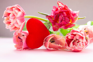 Composition for Valentine's Day and Mother's Day and March 8 Women's Day. Tulip flowers, and two red hearts on a pastel pink background with copy space. Valentine's day, mother's day, women's concept.