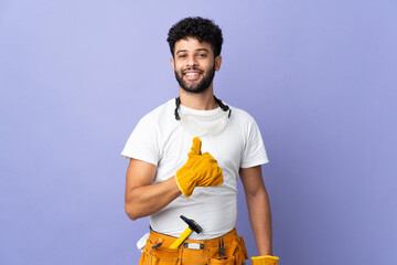 Young electrician Moroccan man isolated on purple background giving a thumbs up gesture