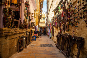Fototapeta na wymiar A narrow street with local artifacts for sale within Jaisalmer fort, Rajasthan, India.