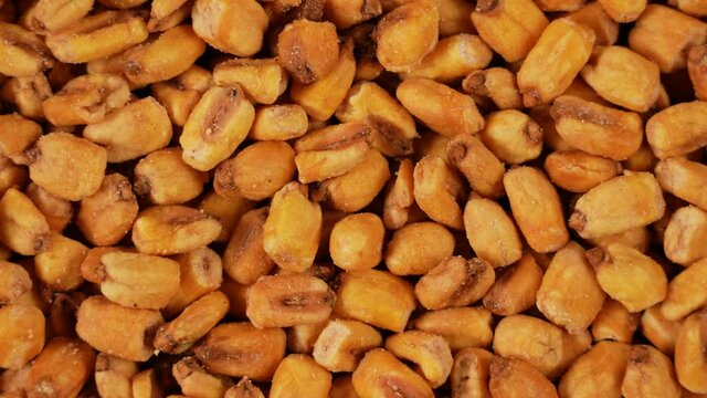 Close-up view 4k stock video footage of tasty bright orange organic salted fried dried corn seeds isolated. Food video background