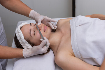young woman lying on a stretcher in an aesthetic center performing beauty treatment and facial...