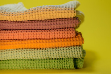  A pile of colorful linen kitchen towels on a yellow background. 