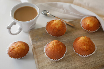 Delicious muffins with a mug of milk and coffee on rustic background