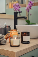 Burning candles in glass jars in modern bathroom