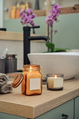 Burning candles in glass jars in modern bathroom