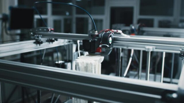 Time lapse modern 3D printer printing model from plastic in workshop of professional design studio