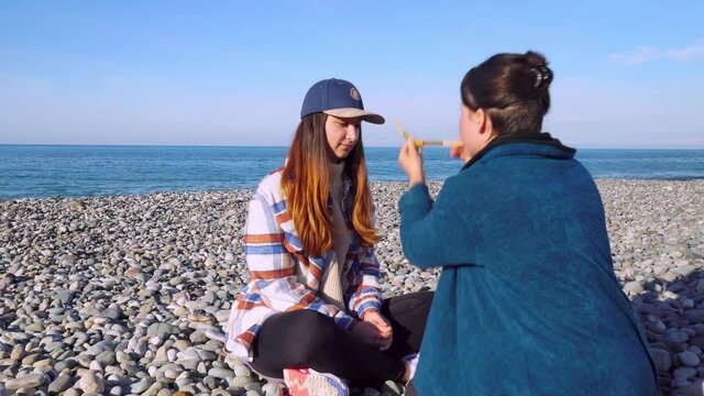 woman pours powder on palm of her hand, wooden tray with Peruvian sacred palo Santo tree, feathers other attributes of rape on pebble beach.Esoteric objects for meditation. Antistress and relaxation