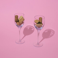 Wine corks in Wine glasses stand on pastel pink background. Squarel composition, minimal retro style enjoying wine concept