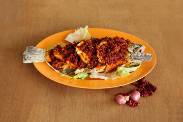 Fried Sambal Belachen Sole Fish with chili pepper Chinese Pomfret in orange dish on wooden background top view fish