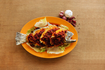 Fried Sambal Belachen Sole Fish with chili pepper Chinese Pomfret in orange dish on wooden background top view fish