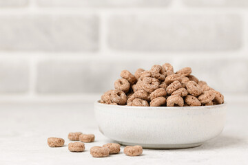 Bowl with chocolate corn or oat rings on light table. Whole grain breakfast cereals with copy space