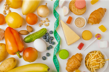 Various useful and unhealthy food items with measuring tape on white background. Diet opposition...