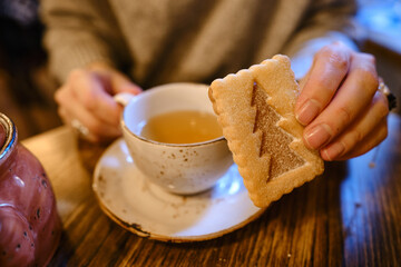 A woman with a cup of tea sits in a cozy cafe with a sweet cookie in her hands. Delicious traditional desserts