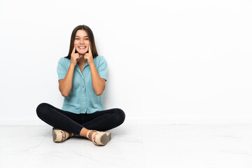 Fototapeta na wymiar Teenager girl sitting on the floor smiling with a happy and pleasant expression