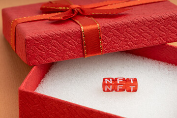 in a red gift box with a red ribbon, cubes with the letters NFT