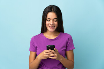 Teenager girl isolated on pink background sending a message or email with the mobile