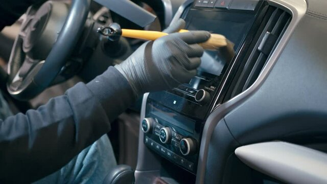 Close up of worker hand cleaning auto interior with special brush from dust, close up. Car detailing or premium car wash