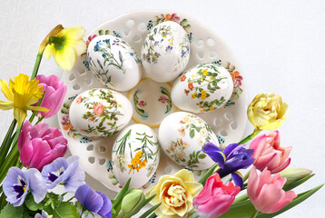 Fototapeta na wymiar Easter postcard with decorated eggs on a decorative plate and different flowers