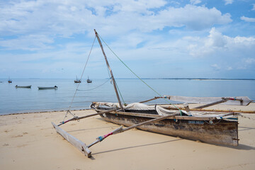 Fototapeta na wymiar An old handmade African dhow fishing wooden boat on the beach. Outrigger canoe, traditional Vezo fishing boat 
