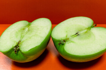Apple cut in half. Sliced green apple on a red background