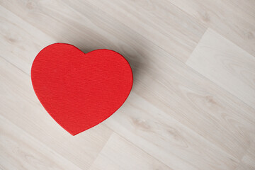 A gift box in the form of a red heart stands on a wooden floor. Valentine's Day - February 14