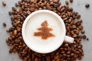 white cup of coffee cappuccino on a concrete background next to coffee beans