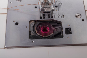 sewing machine. a foot and a needle with a thread in the center of attention. close-up. there is a slight tinting of the frame