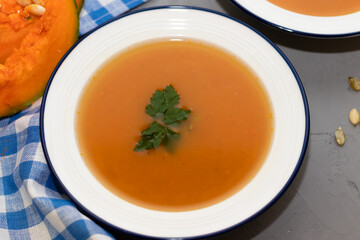 two plates of pumpkin soup on a concrete background and a napkin in a checkered blue